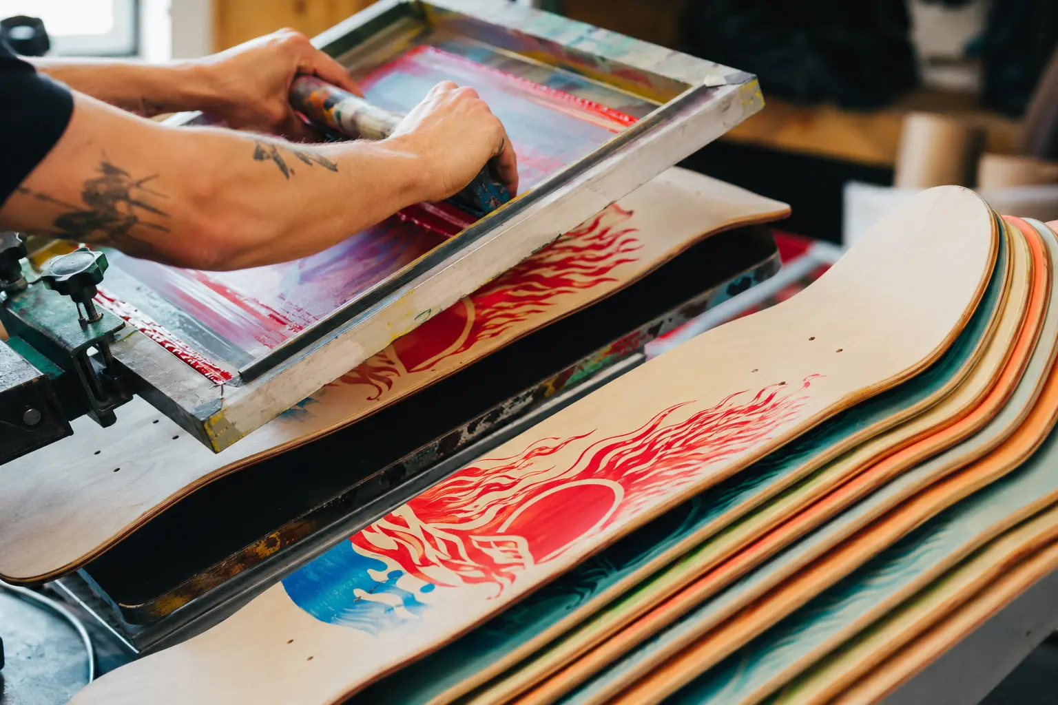 A craftsperson screen-printing original graphics onto skateboard decks