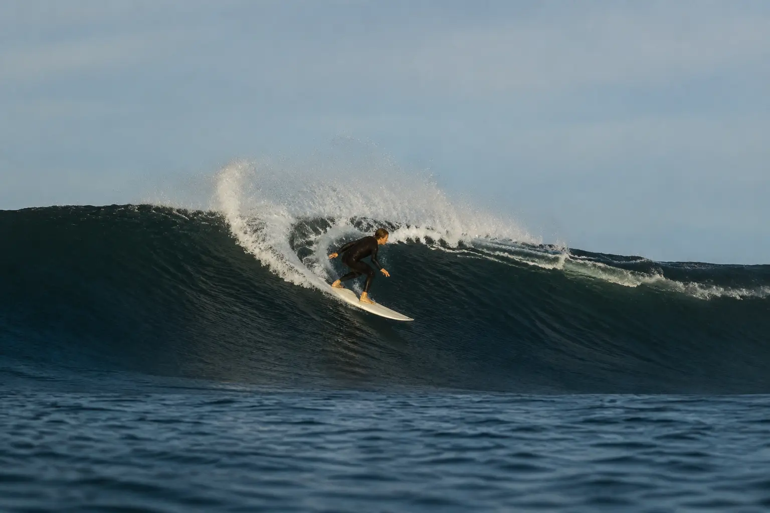A surfer carving a bright line with the full board in view
